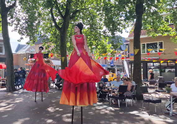 Steltenlopers in rode en oranje kostuums op een plein