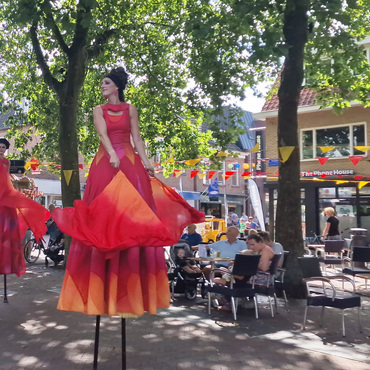 Steltenlopers in rode en oranje kostuums